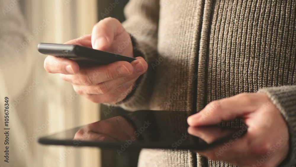 Smartphone and tablet data synchronization, man syncing files and documents on personal wireless electronic devices at home.