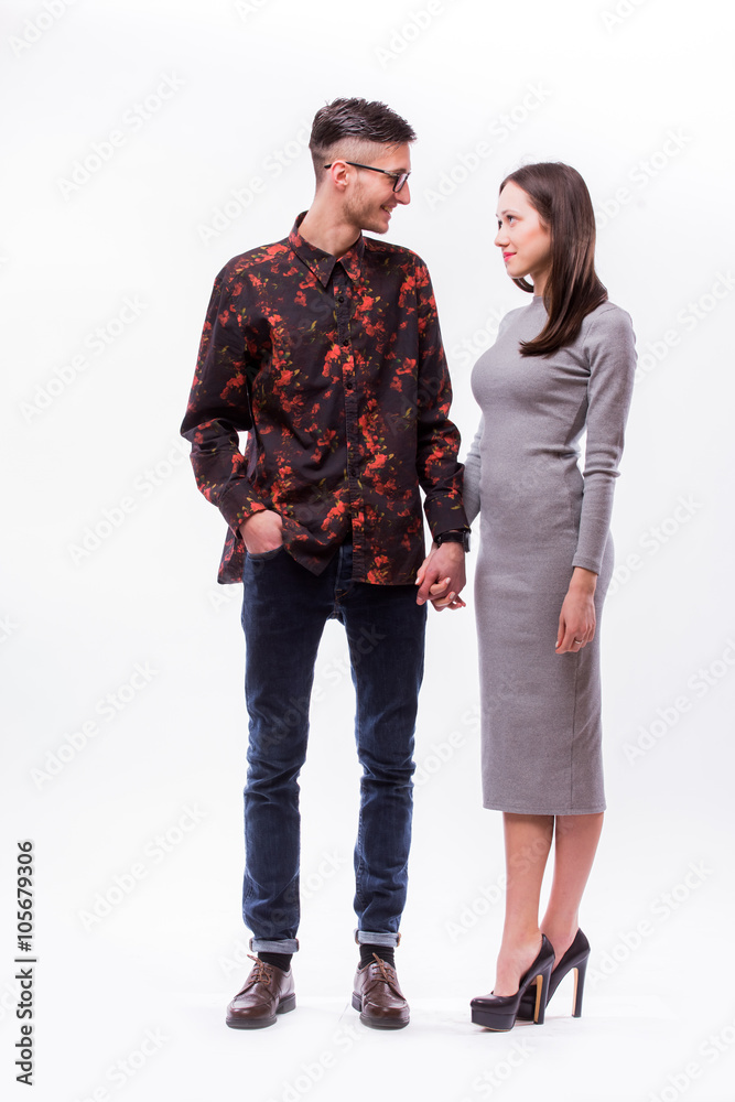 Happy hipster couple holding hands and look each other against white background Happy hipster couple holding hands and look each other against white background
