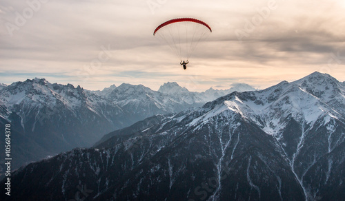 Paraglider flight over the snow-capped peaks of the Caucasus mountains