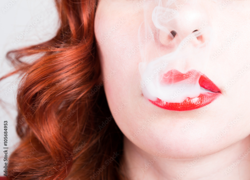 Fototapeta premium close-up portrait of a elegant young redhead woman, bright red lips, the smoke releases