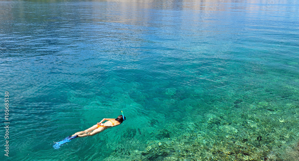 Young woman snorkeling in transparent shallow sea