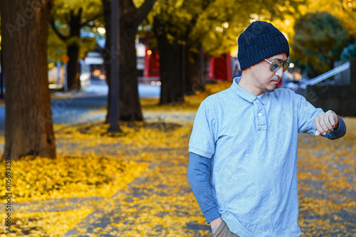 An asian man in a polo t-shirt walks on a street