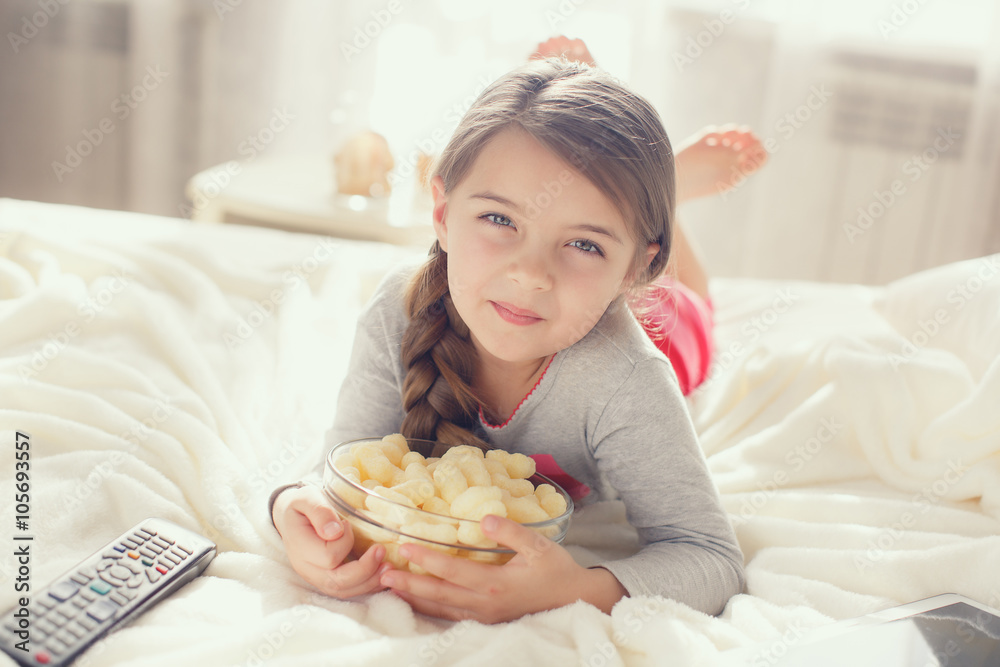 Little girl eating popcorn in bed