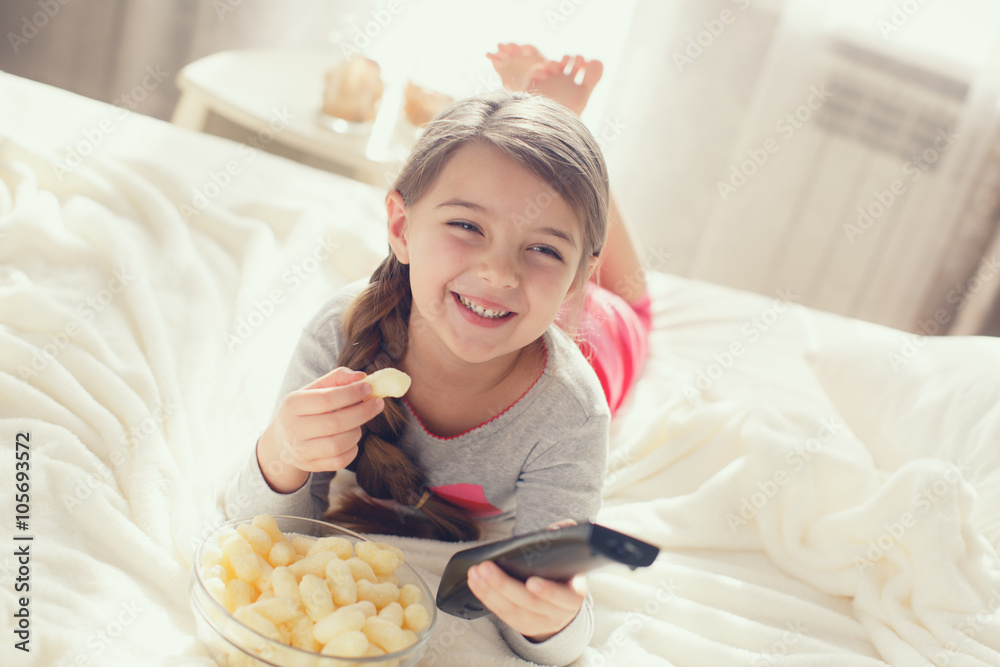 Little girl eating popcorn in bed
