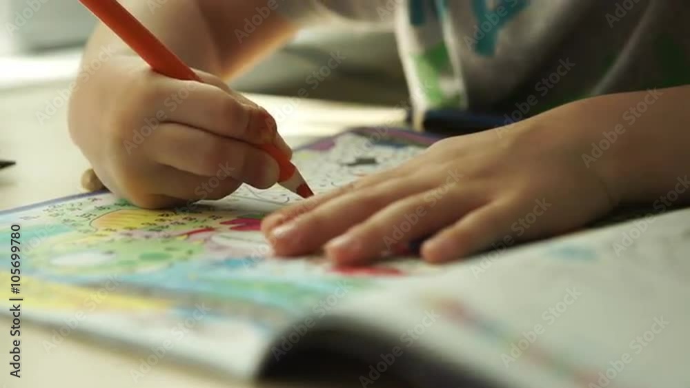Child hands paints a orange pencils on a paper Child hands paints a orange pencils on a paper