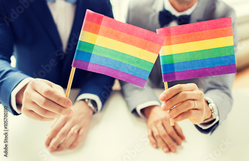 close up of male gay couple holding rainbow flags