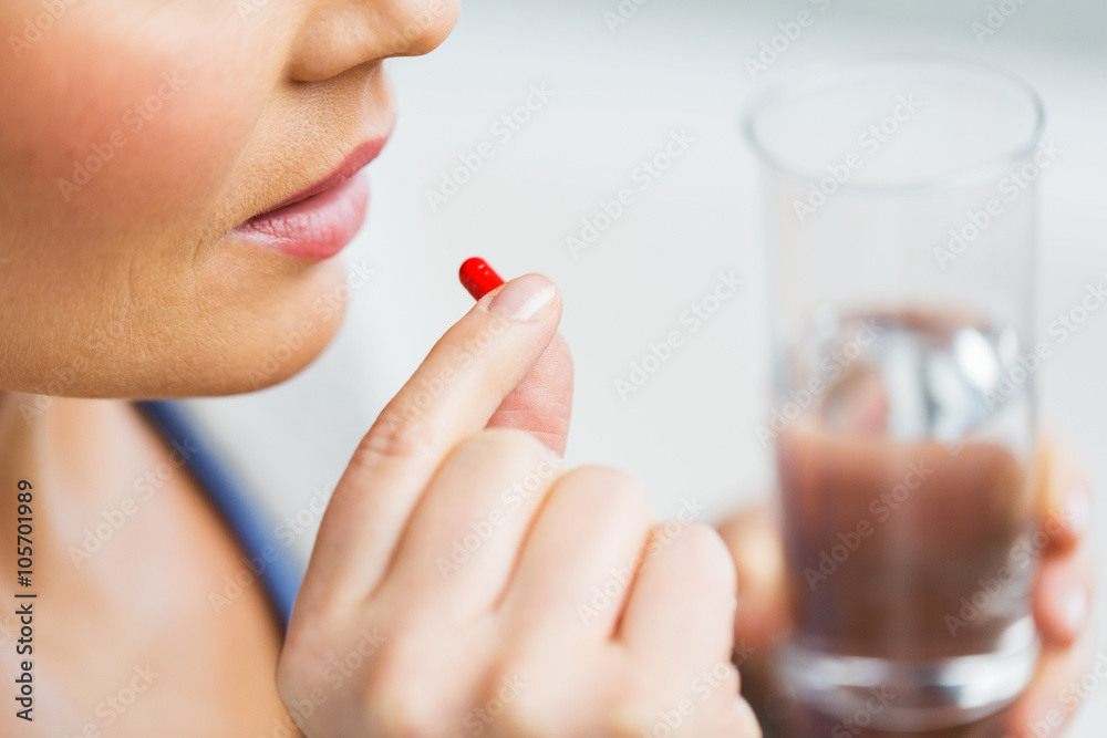 close up of woman taking medicine in pill