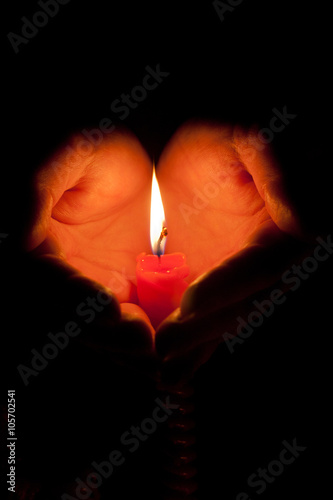 Hands cupped around a burning candle