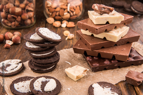 Шоколадное печенье и шоколад с орехами на темной деревянной доске
