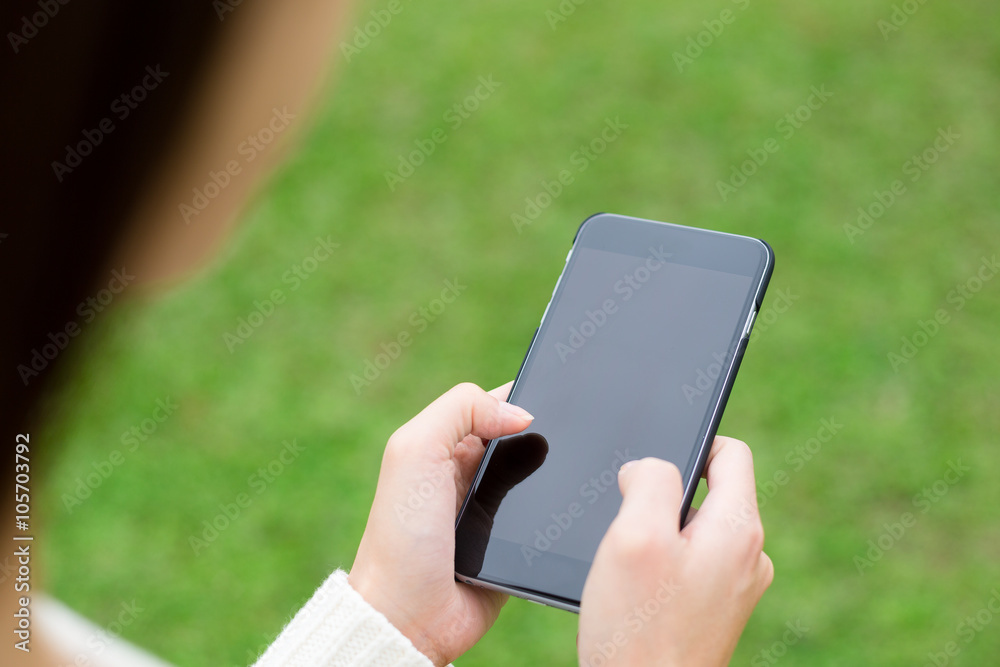 Woman use of cellphone over green grass