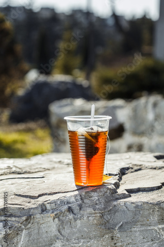 fresh tea in a disposable plastic cup with a spoon and a bag on