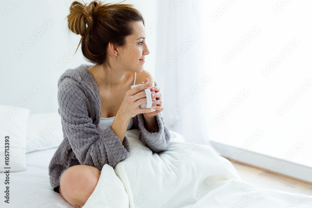 Beautiful young woman drinking coffee on bed. Beautiful young woman drinking coffee on bed.