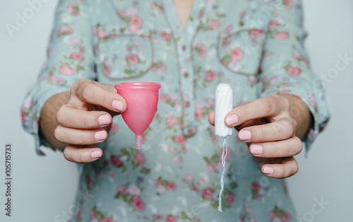 Woman hands comparing menstrual cup with a tampon photo