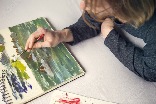 young man lying in bed painting a picture