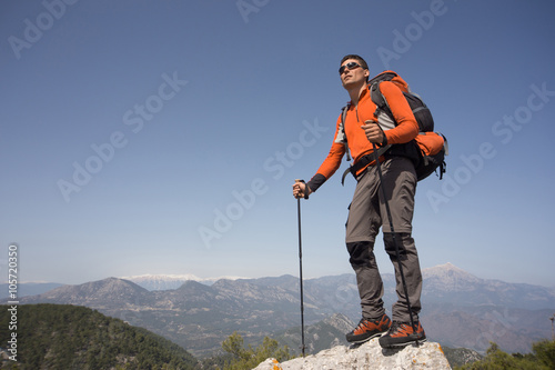 Young man with backpack on a mountain top on a sunny day.