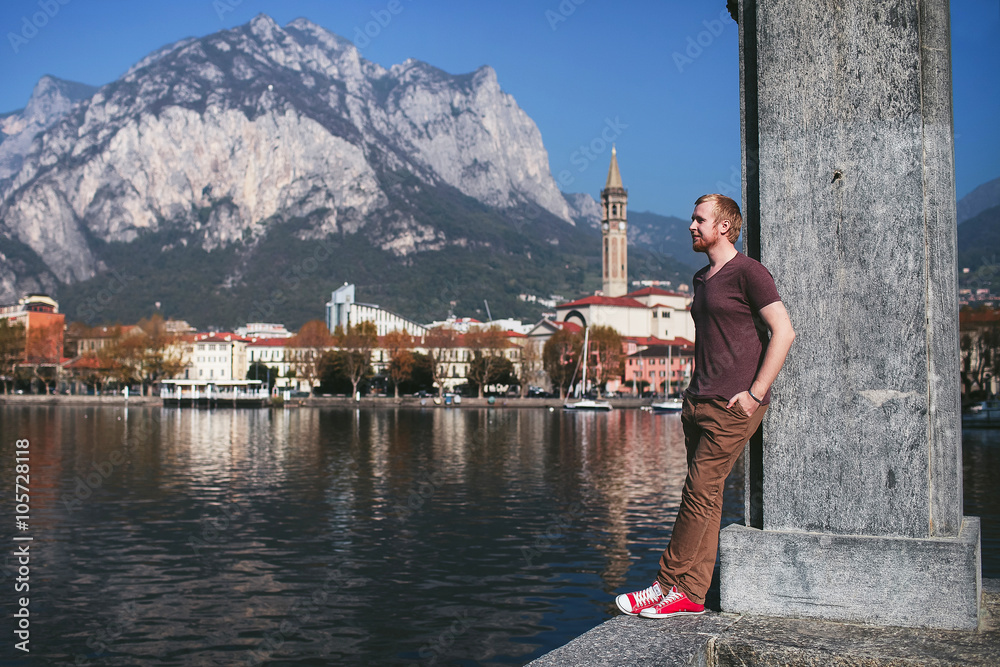 man stands on the promenade overlooking the city of mountain Lake Como