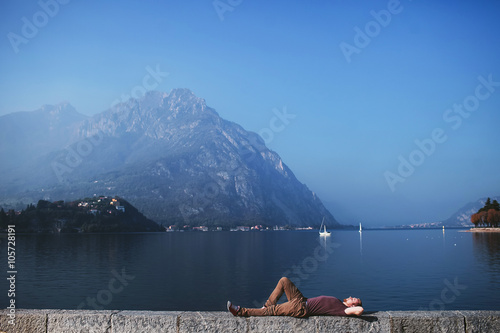 man lying on the embankment of a mountain lake Como