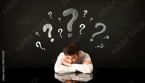 Sitting businessman under question marks