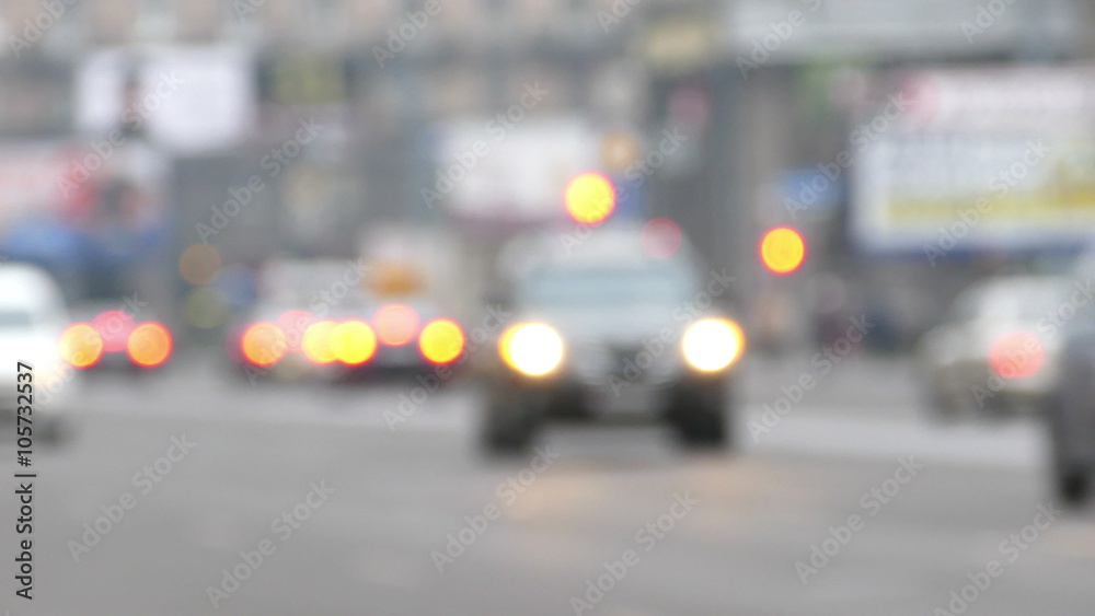 Defocused View of Cars Moving Through Street at Blurred City Lights Background