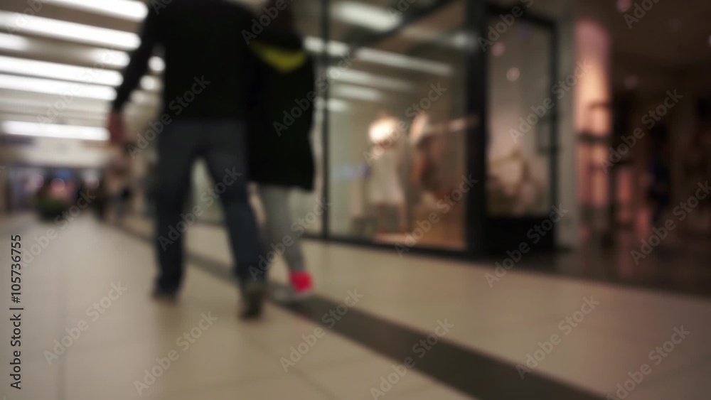 Slowed unidentifiable,unrecognizable,out of focus people going through shopping mall corridor with blurred,defocused stores in background Slowed unidentifiable,unrecognizable,out of focus people going through shopping mall corridor with blurred,defocused stores in background