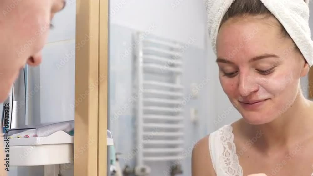 Woman applying mask cream on face in bathroom 4K