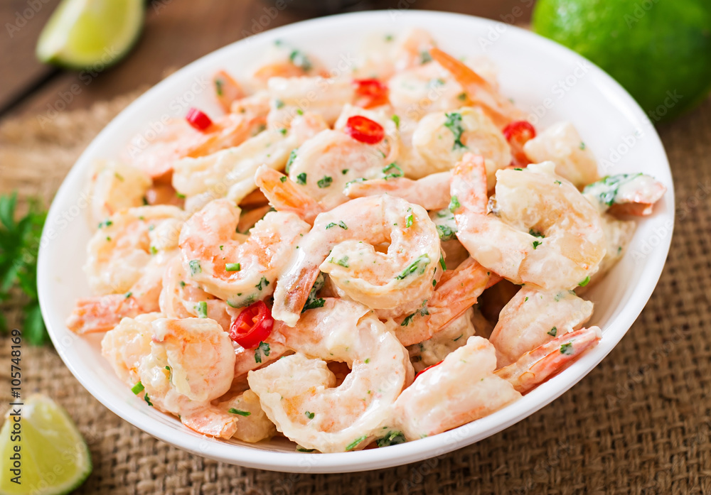 Shrimp in a creamy garlic sauce with parsley and lime in white bowl