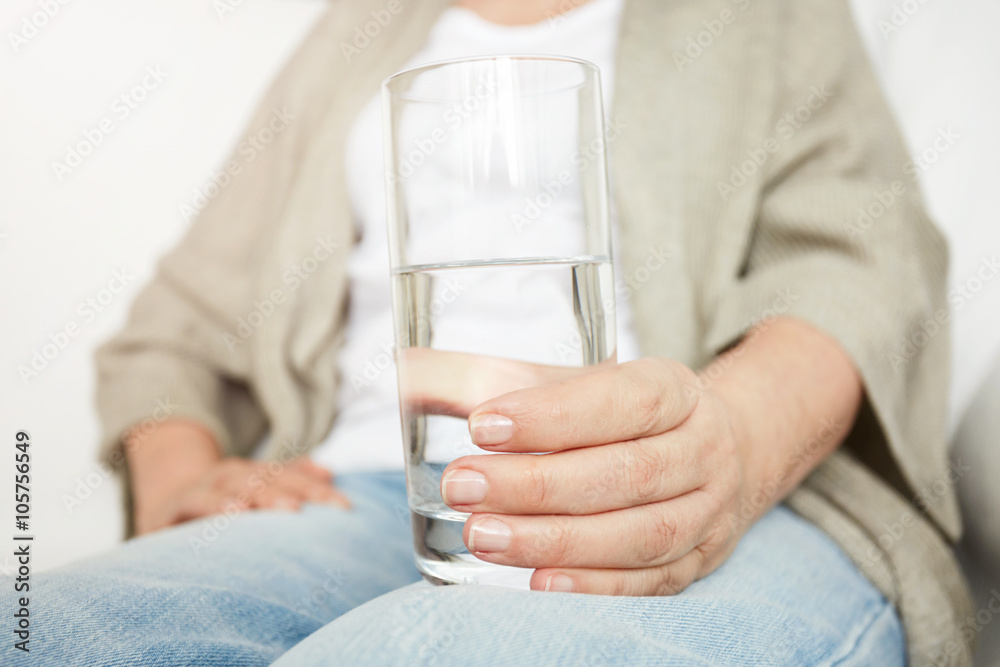 Close up of mature woman's hand keeps a glass of water Close up of mature woman's hand keeps a glass of water