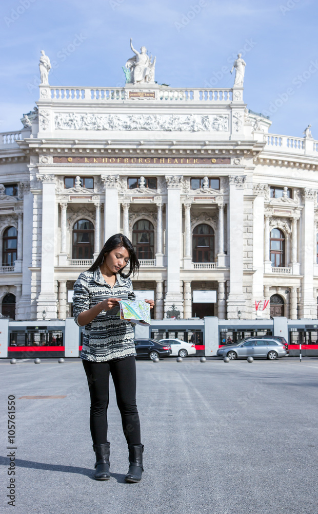 Asian woman studying a map on the square near the theater, Vienna