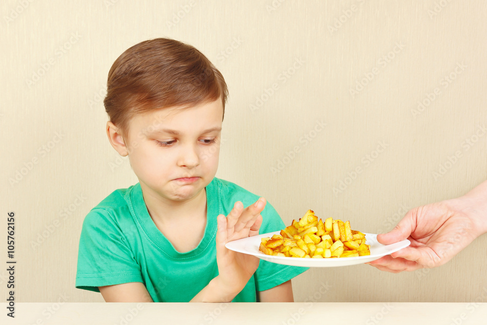 Little cute unhappy boy refuses to eat a french fries Little cute unhappy boy refuses to eat a french fries