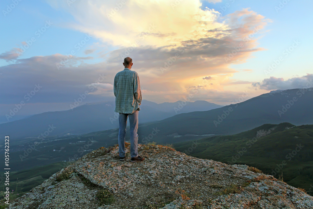 A man stands on top of the evening and looking at the village be