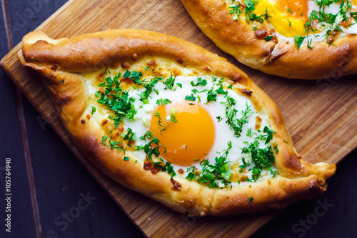 Beautiful open pies khachapuri with egg and onions on wooden background