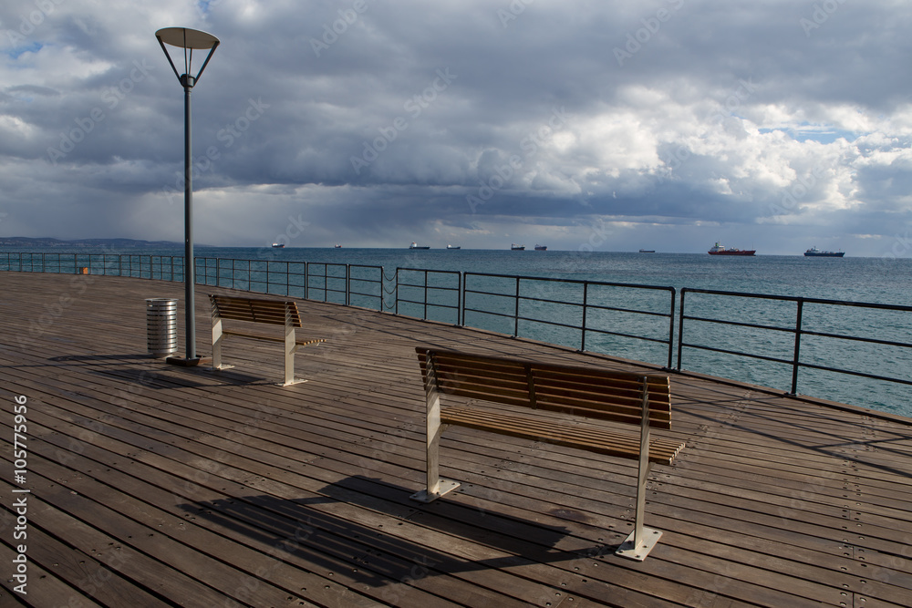 Wooden pier on the beach. Ships at sea. Limassol's seafront promenade. Cyprus.