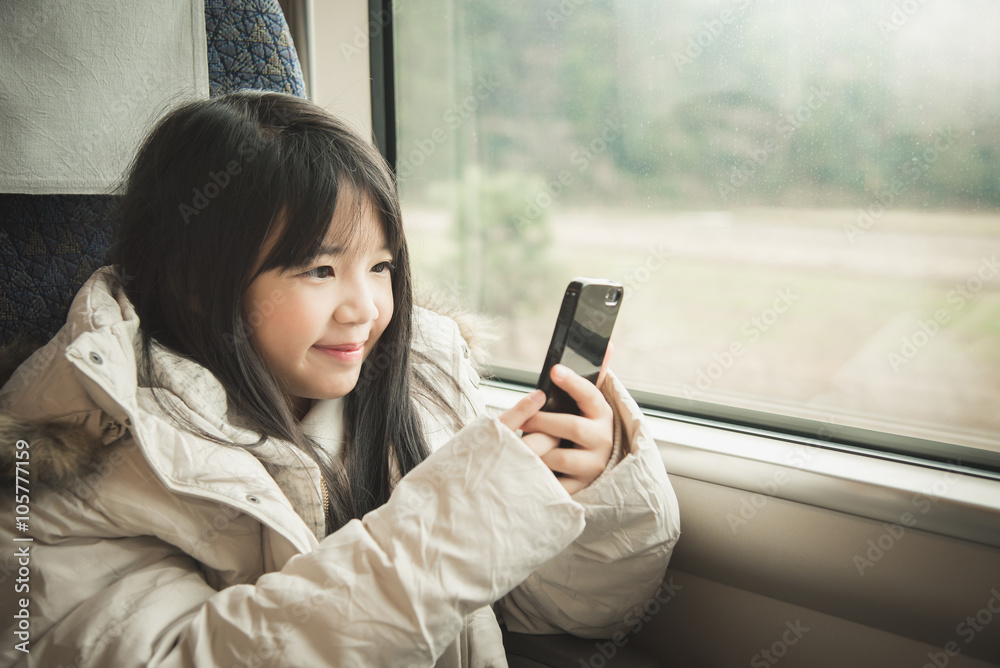 Little asian girl smiling and sharing social media in a smart ph Little asian girl smiling and sharing social media in a smart ph