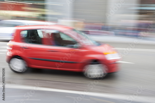 Red car in motion blur, car driving fast in city