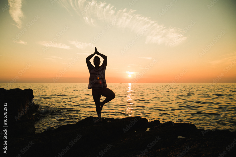 Silhouette of yoga adult man stand on one lag on the beach at sunset time
