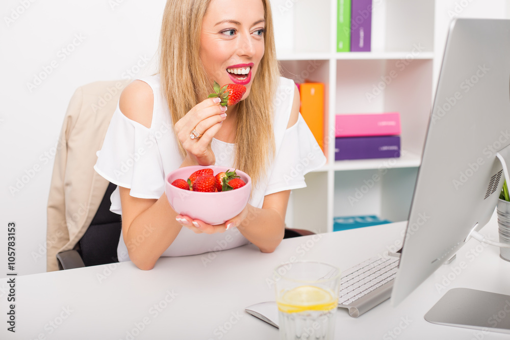 Woman working at the office and eating strawberries Woman working at the office and eating strawberries