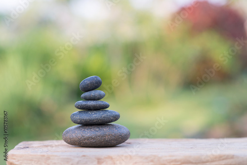  Zen stones on wood table with garden blurred background.