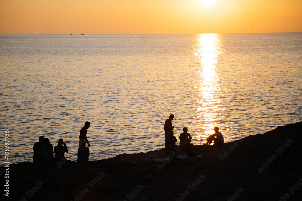 Fototapeta premium People silhouettes on the beach at sunset time