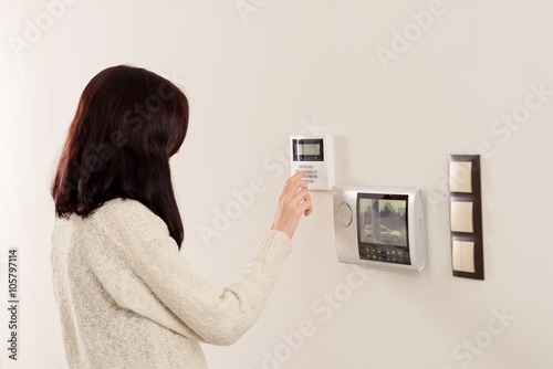 woman entering code on keypad of home security alarm photo