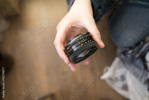 Hand holding manual prime lens 50 mm on dark background