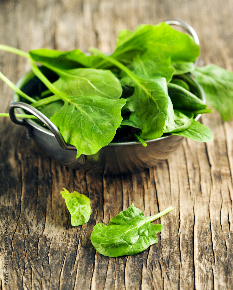 Fototapeta premium Fresh spinach in bowl on wooden background. Selective focus