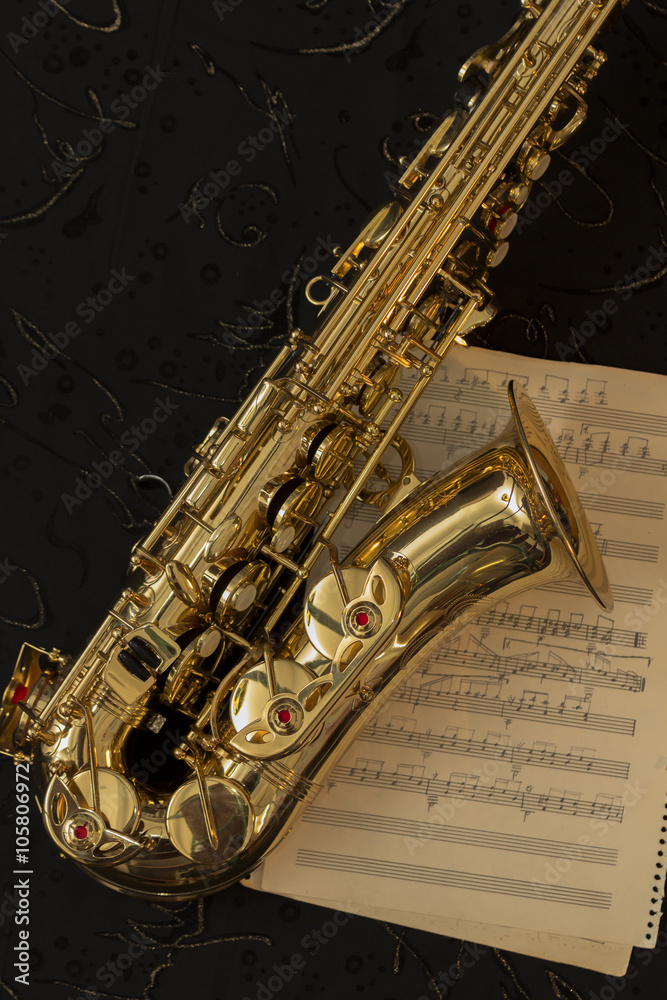 Naklejka premium Golden saxophone and music sheets on a black background