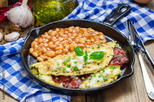 Bacon stuffed omelette with backed beans on a iron cast pan