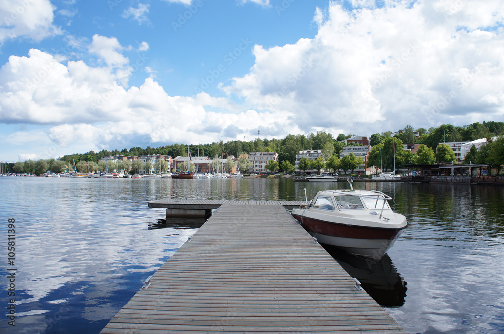 planked footway on lake with boat in summer day 