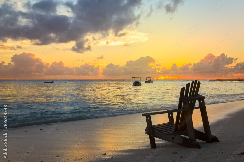 Beach chair on the coast line by sunset Beach chair on the coast line by sunset