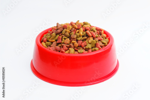 Red pet feeder / bowl filled with dry kibble on isolated background