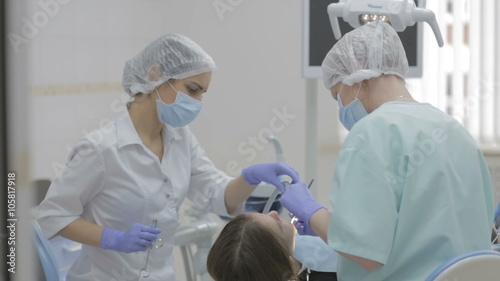 Dentist and dental nurse at work on a reclining patient.