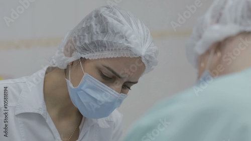 Dentist and dental nurse at work on a reclining patient.