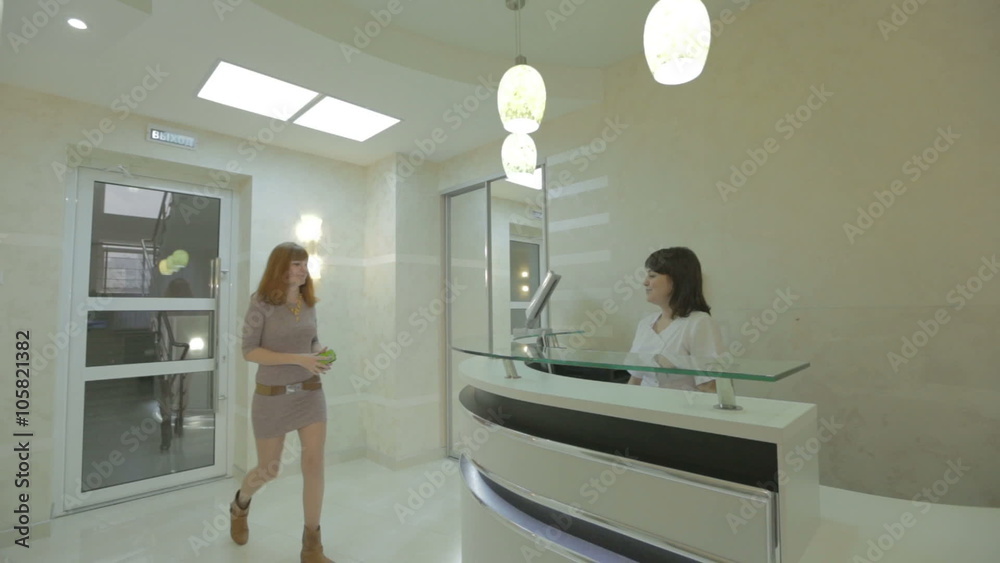 Patient and nurse conversing at hospital reception desk