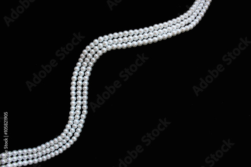 White pearl necklace on the black background